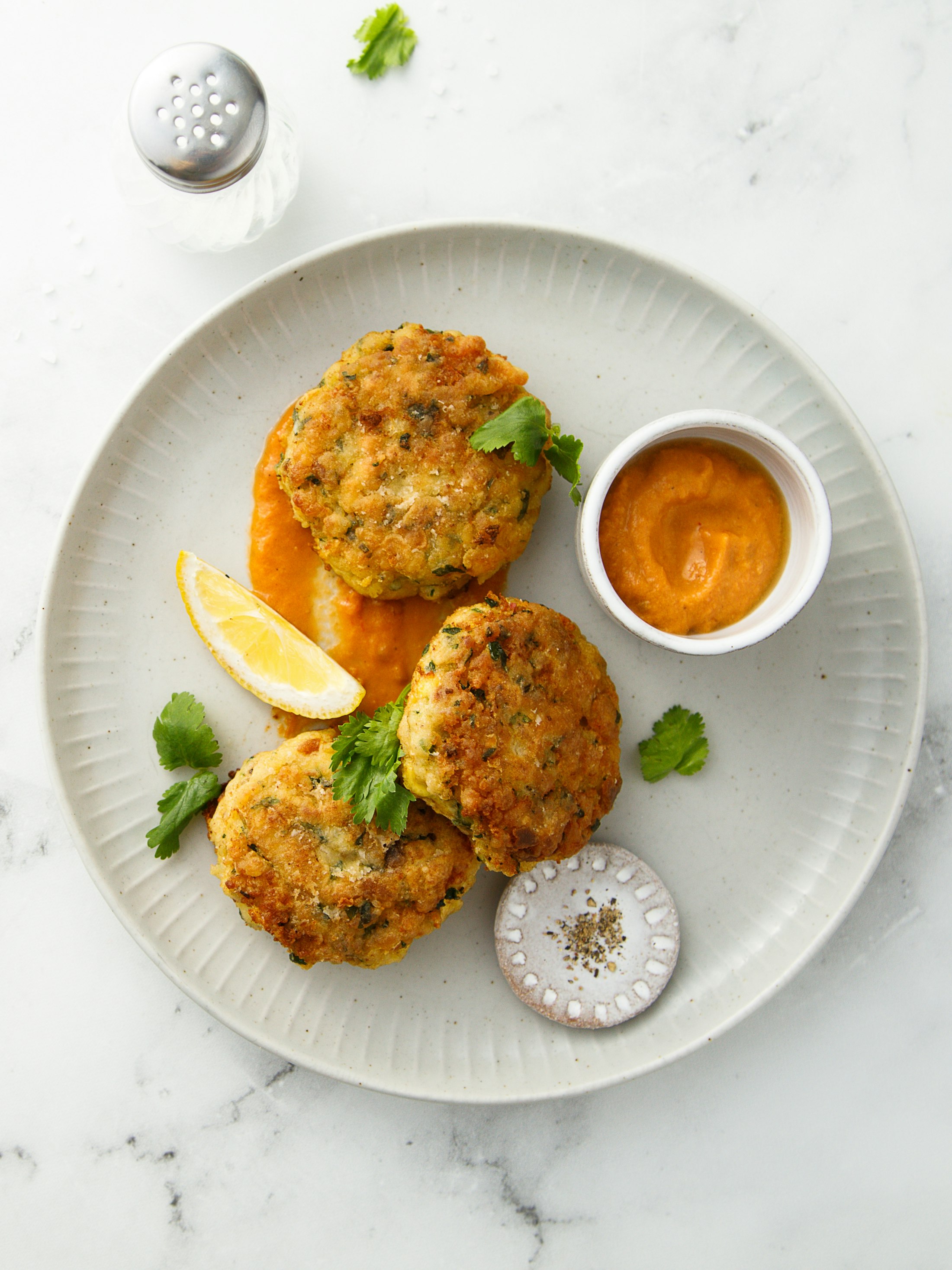 Crab cakes on a white dish with a side of dipping sauce